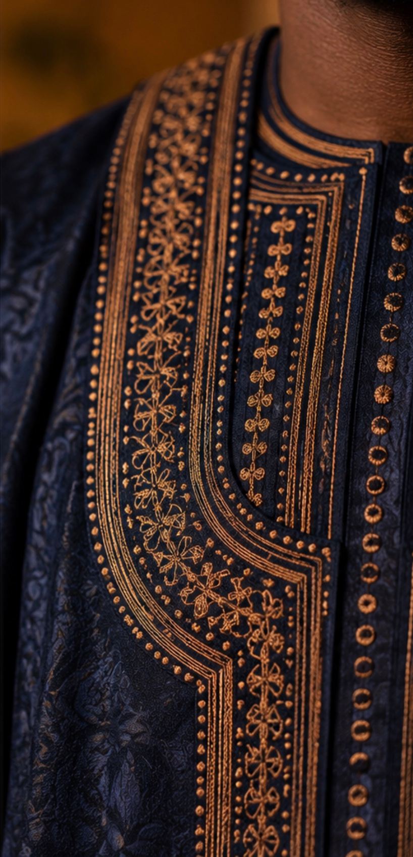 Close-up of bronze thread embroidery on midnight-blue fabric.